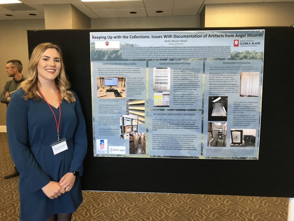 Molly stands next to her poster "Keeping UP with the Collections: issues with documentation of artifacts from Angel Mounds"