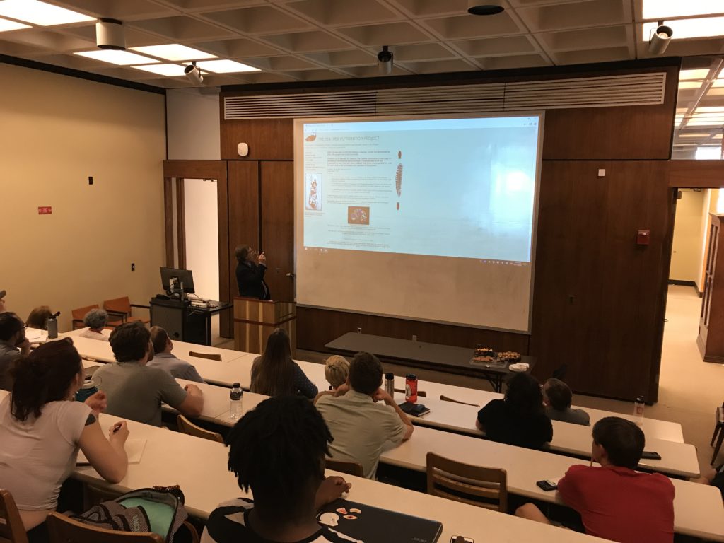 Image from back of lecture hall towards Jonathan Reyman pointing at screen.