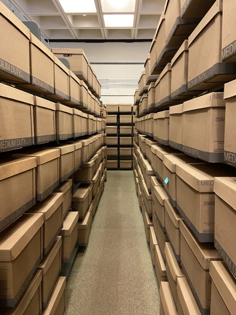 Image down library aisle full of brown boxes.